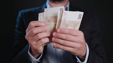 Bir adam siyah ceket ve beyaz gömlek nakit Holding