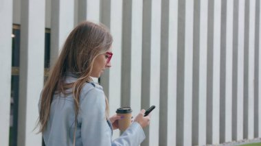 Bir genç bayan yürüyüş ve bir Smartphone kullanarak