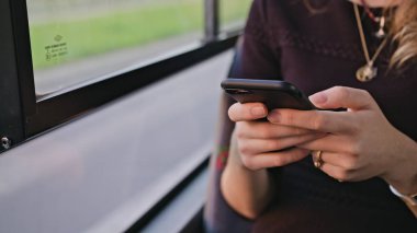 Otobüste akıllı telefon kullanan genç bir bayan.