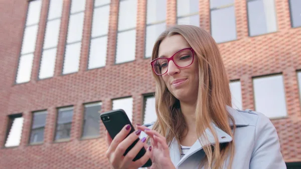 Una joven usando un teléfono inteligente cerca del edificio — Foto de Stock