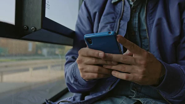 Молодой человек, использующий смартфон в автобусе — стоковое фото