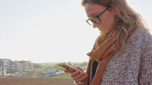 En ung dam med en Smartphone utomhus — Stockfoto