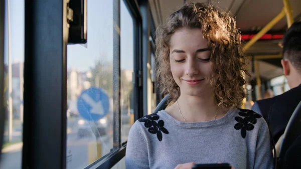 En ung dam som använder en smartphone på bussen — Stockfoto