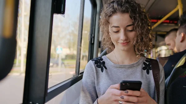 En ung dam som använder en smartphone på bussen — Stockfoto