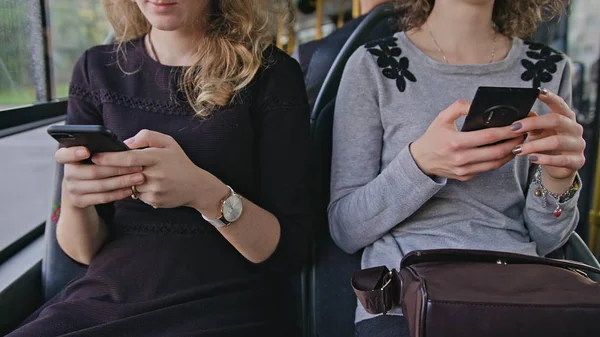 Две юные леди используют смартфоны в автобусе — стоковое фото