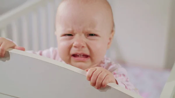 Bebê em pé em um berço em casa. Chorando — Fotografia de Stock