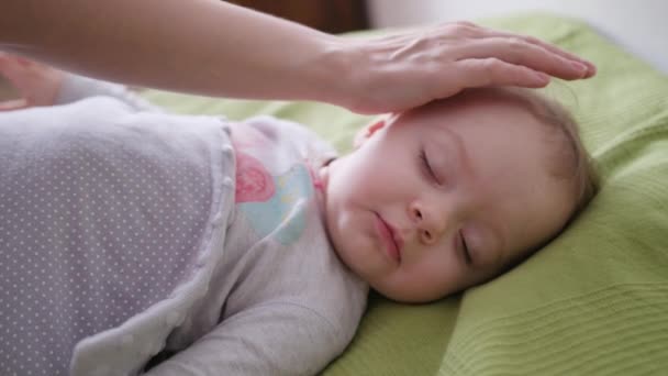 Manos femeninas cubriendo a un bebé acostado en la cama — Vídeos de Stock