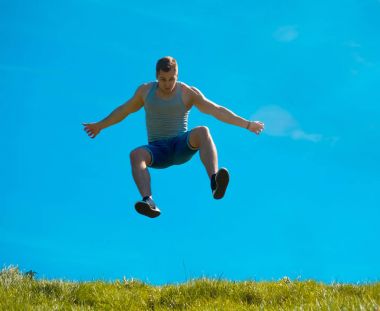 Zıplayan adam kadar. Arka plan mavi gökyüzü. Yeşil çimen