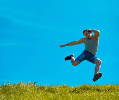 Zıplayan adam kadar. Arka plan mavi gökyüzü. Yeşil çimen