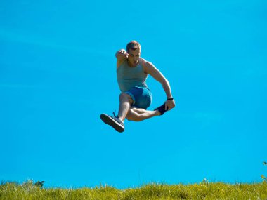 Zıplayan adam kadar. Arka plan mavi gökyüzü. Yeşil çimen