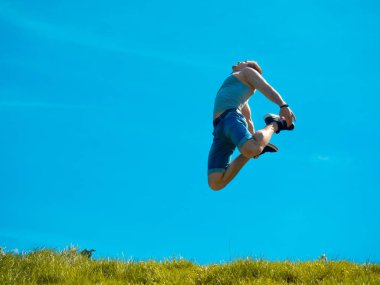 Zıplayan adam kadar. Arka plan mavi gökyüzü. Yeşil çimen