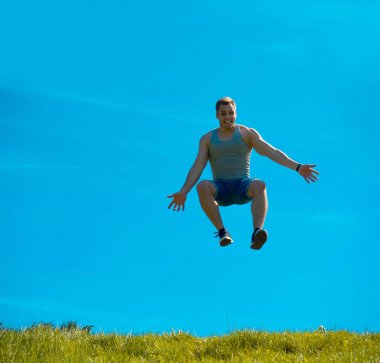 Zıplayan adam kadar. Arka plan mavi gökyüzü. Yeşil çimen