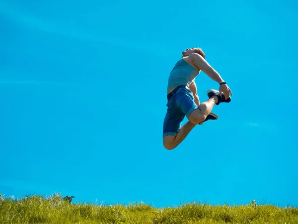 Прыгающий парень. Голубое небо. Под зеленой травой — стоковое фото