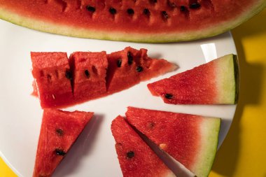 Sarı bir arka plan üzerinde beyaz bir tabakta karpuz yalan dilimlenmiş