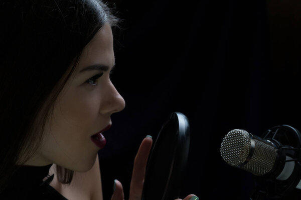 Beautiful girl singing In Recording Studio with microphone