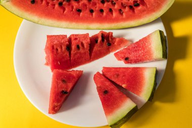 Sarı bir arka plan üzerinde beyaz bir tabakta karpuz yalan dilimlenmiş