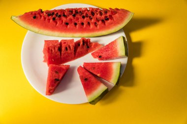 Sarı bir arka plan üzerinde beyaz bir tabakta karpuz yalan dilimlenmiş