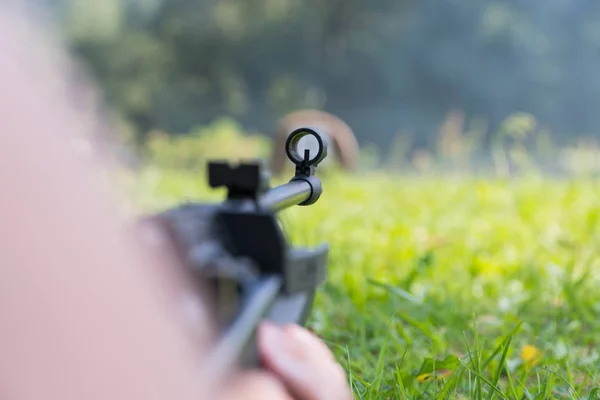 Um homem dispara um alvo de uma arma pneumática. Uma vista de trás do ombro — Fotografia de Stock