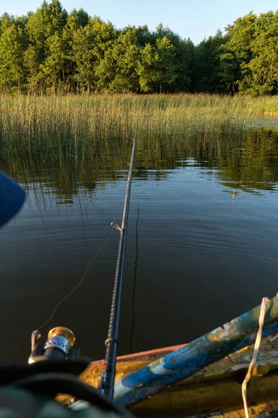 Um homem está pescando de um barco. Vista de trás do ombro de um homem, você pode ver a vara de pesca e o flutuador — Fotografia de Stock