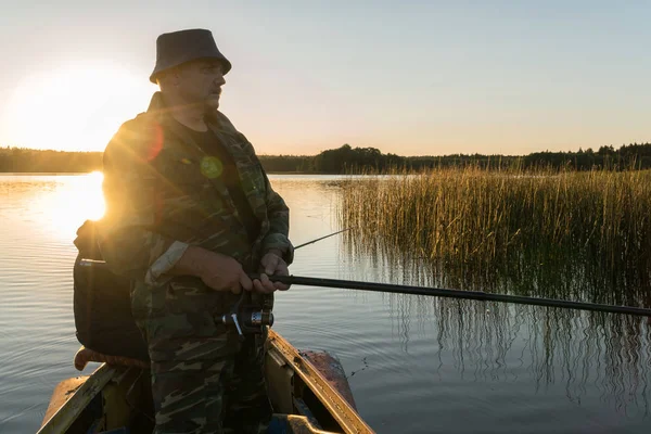 Ein Mann fischt bei Sonnenuntergang von einem Boot aus — Stockfoto