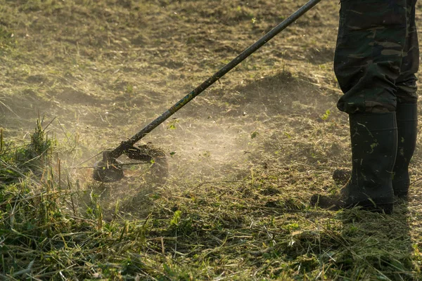 Um homem corta a relva no jardim com um aparador — Fotografia de Stock