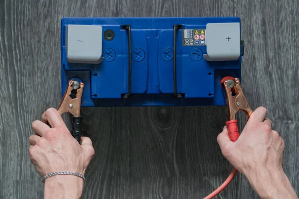 Die männliche Hand verbindet die Klemmen mit den Autobatterien auf einem Holzuntergrund — Stockfoto
