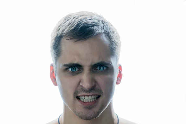 Der unrasierte junge Mann beißt die Zähne vor weißem Hintergrund zusammen. Der Kerl zeigt Wut — Stockfoto