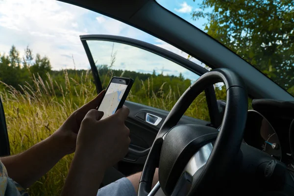 Kierowca zgubił drogę. Człowiek próbuje znaleźć sposób na nawigatora w telefonie komórkowym. Pola w tle — Zdjęcie stockowe