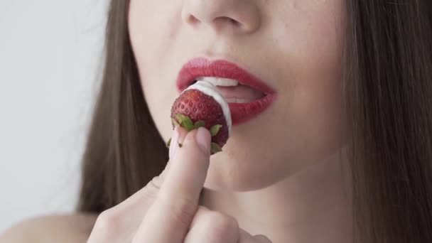 Girl eating strawberries with cream. Red lips. Slow motion.