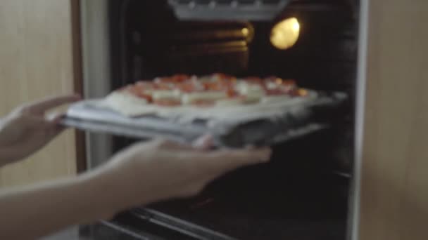 Het meisje is het koken van pizza. De kok zet pizza in de oven — Stockvideo