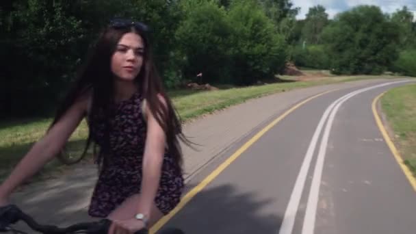 소녀는 자전거를 타고입니다. 전면 보기 숲과 구름 배경 — 비디오