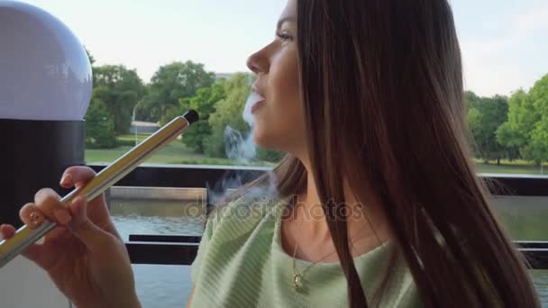 A rapariga fuma um cachimbo num café. Close-up de uma cara — Vídeo de Stock