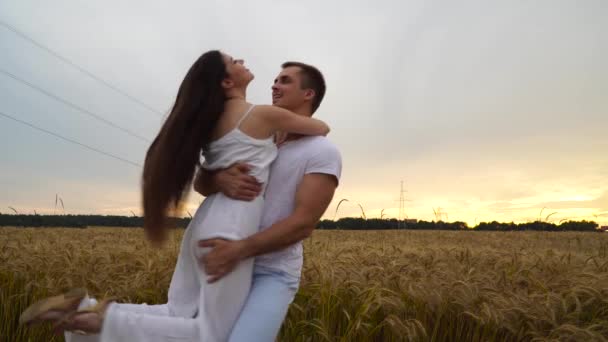 Kluk s holkou v náručí se točí v pšeničné pole při západu slunce