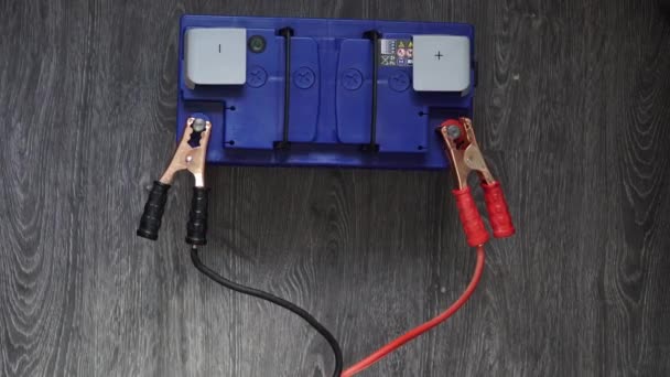 Męskiej ręki odłączyć zaciski do akumulatorów na podłoże drewniane — Wideo stockowe