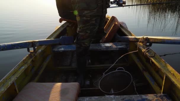 Ein Mann fischt bei Sonnenuntergang von einem Boot aus — Stockvideo