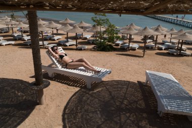 Kız bir tembel Sahilde güneşlenmek. Arka planda bir iskele görülür