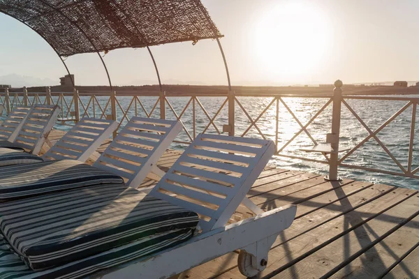 Quai avec chaises longues dans la mer en station balnéaire au coucher du soleil. Vacances d'été. Vue sur une mer claire avec de l'eau turquoise. Vacances d'été au bord de la mer dans un pays exotique — Photo