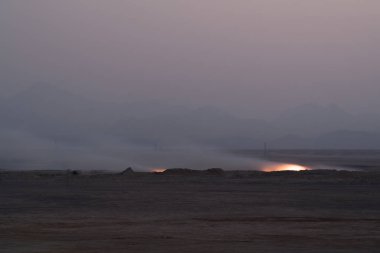 Çölde akşam ateş. Arka planda, dağlar