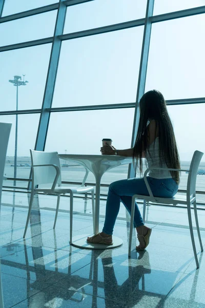 Meisje houdt een glas koffie in de luchthaven business lounge met vliegtuigen — Stockfoto