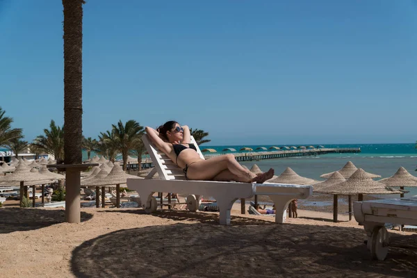 Kız bir tembel Sahilde güneşlenmek. Arka planda bir iskele görülür