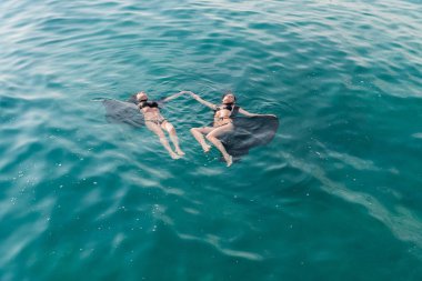 Sırt üstü denizde yüzmek kızlar mayo ve bir pelerin