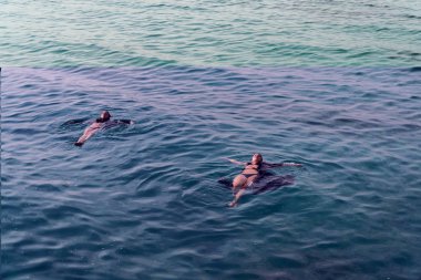 Sırt üstü denizde yüzmek kızlar mayo ve bir pelerin