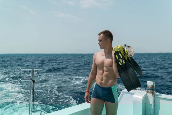 Yüzgeçleri olan stern kaburgalar ve ellerini maskeli adam duruyor. Adam suya dalmaya hazırlanıyor