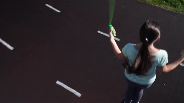 Una chica está saltando la cuerda en una cinta del estadio . — Vídeos de Stock