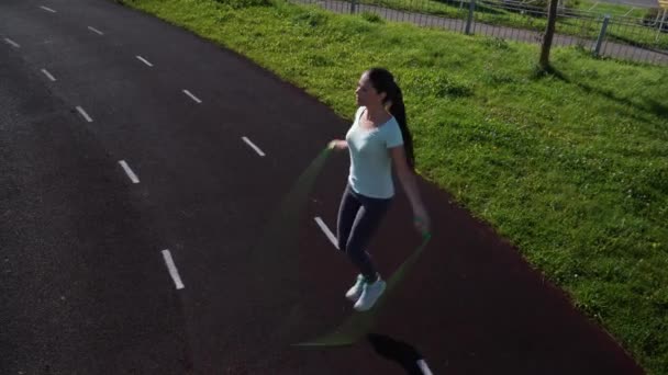 Дівчина стрибає мотузкою на біговій доріжці стадіону . — стокове відео