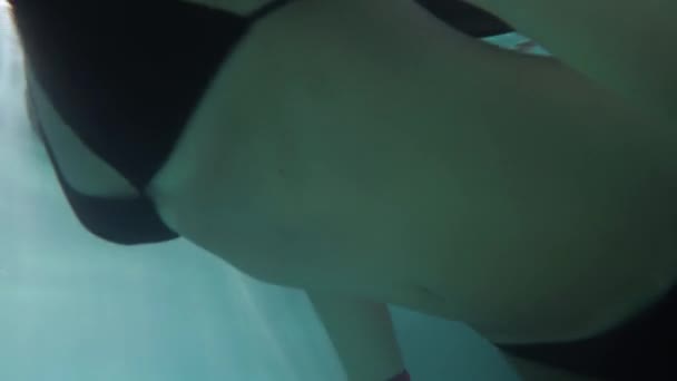 The girl is swimming in the pool. The video camera is under water. — Stock Video