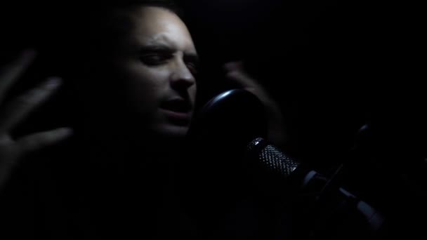 Человек поет в студии звукозаписи с микрофоном . — стоковое видео