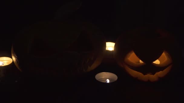 Свечи раздули ветер. Две тыквы на столе, а вокруг горят свечи. Хелоуинский дизайн . — стоковое видео