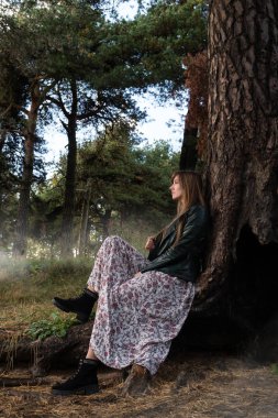 Kız büyük bir ağacın altında ve sis etrafında oturur