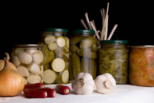 Jars with pickled vegetables on dark background